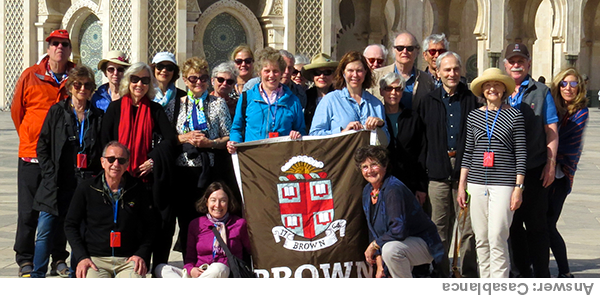 Where in the world did the Brown Travelers go? Travelers posing with a Brown flag in front of a white building with archways and patterns. Answer: Casablanca