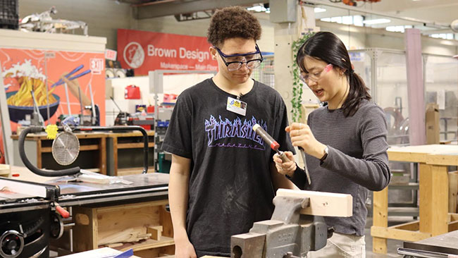 Brown student teaching a high school student in the Brown Design Workshop