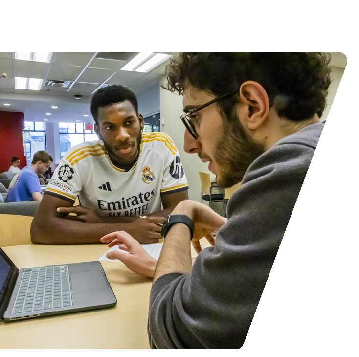 peer advisor with laptop advising another student