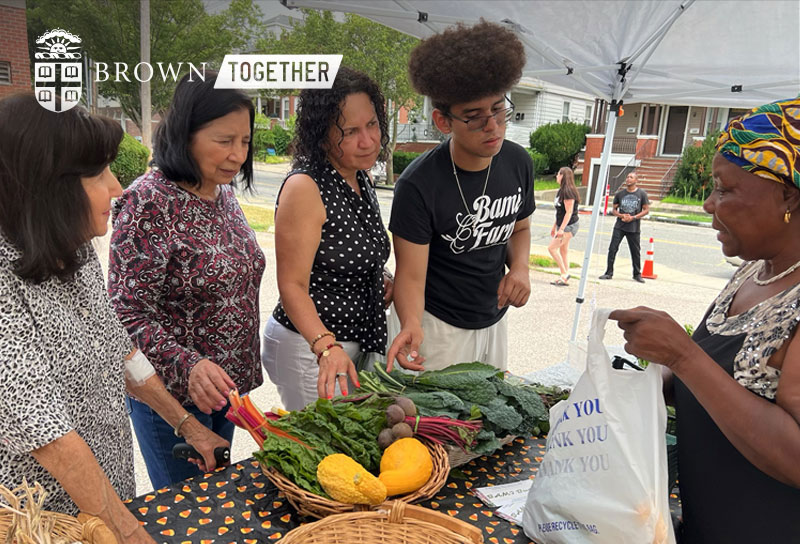Brown Together logo superimposed on photo of Brown student Michael Ochoa selecting vegetables at an outdoor market