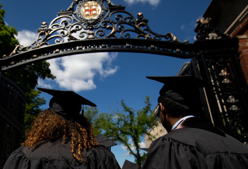 two students walk through Van Wickle gates at their commencement