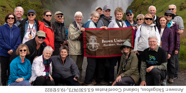 A group of Brown Travelers in Skógafoss, Iceland Coordinates 63.5307473,-19.512822 with a Brown University banner.