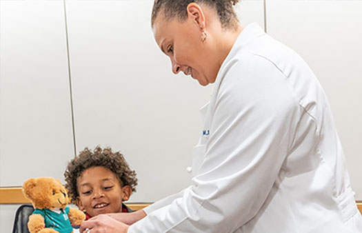 Dr. Sabina Holland shows students (including her son, Giles) how to put a cast on a teddy bear.