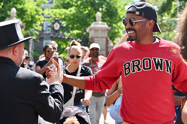 alumnus wearing Brown sweatshirt high-fiving other alumni during Procession