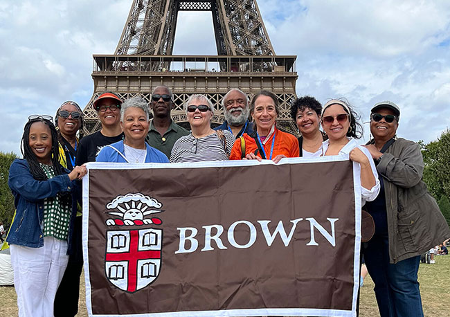 group of Brown alumni posing with Brown banner in front of the Eiffel Tower