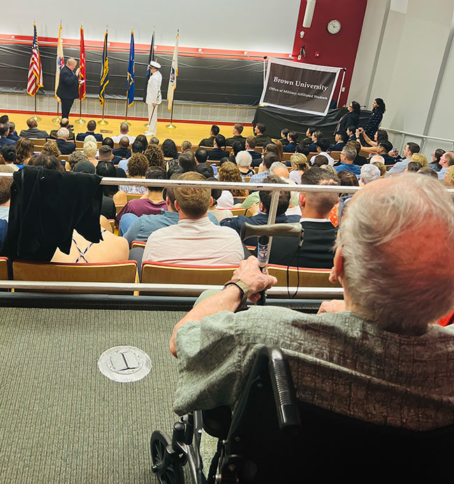 George Montgomery looks on as Mark Montgomery and Jack Montgomery stand on stage in auditorium