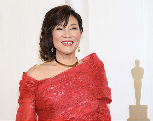 smiling Janet Yang in gown with shadow of an Oscar statue