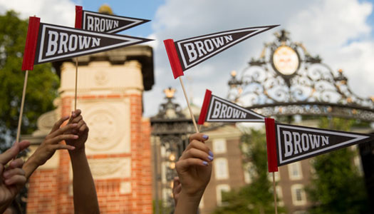hands holding Brown pennants in front of Van Wickle gates